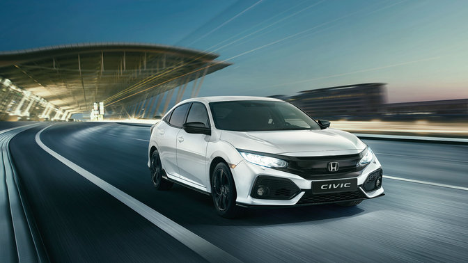 Vue de trois quarts avant de la Honda Civic Sport Line, roulant dans un paysage urbain.