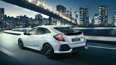 Vue de trois quarts arrière de la Honda Civic Sport Line, roulant dans un paysage urbain.