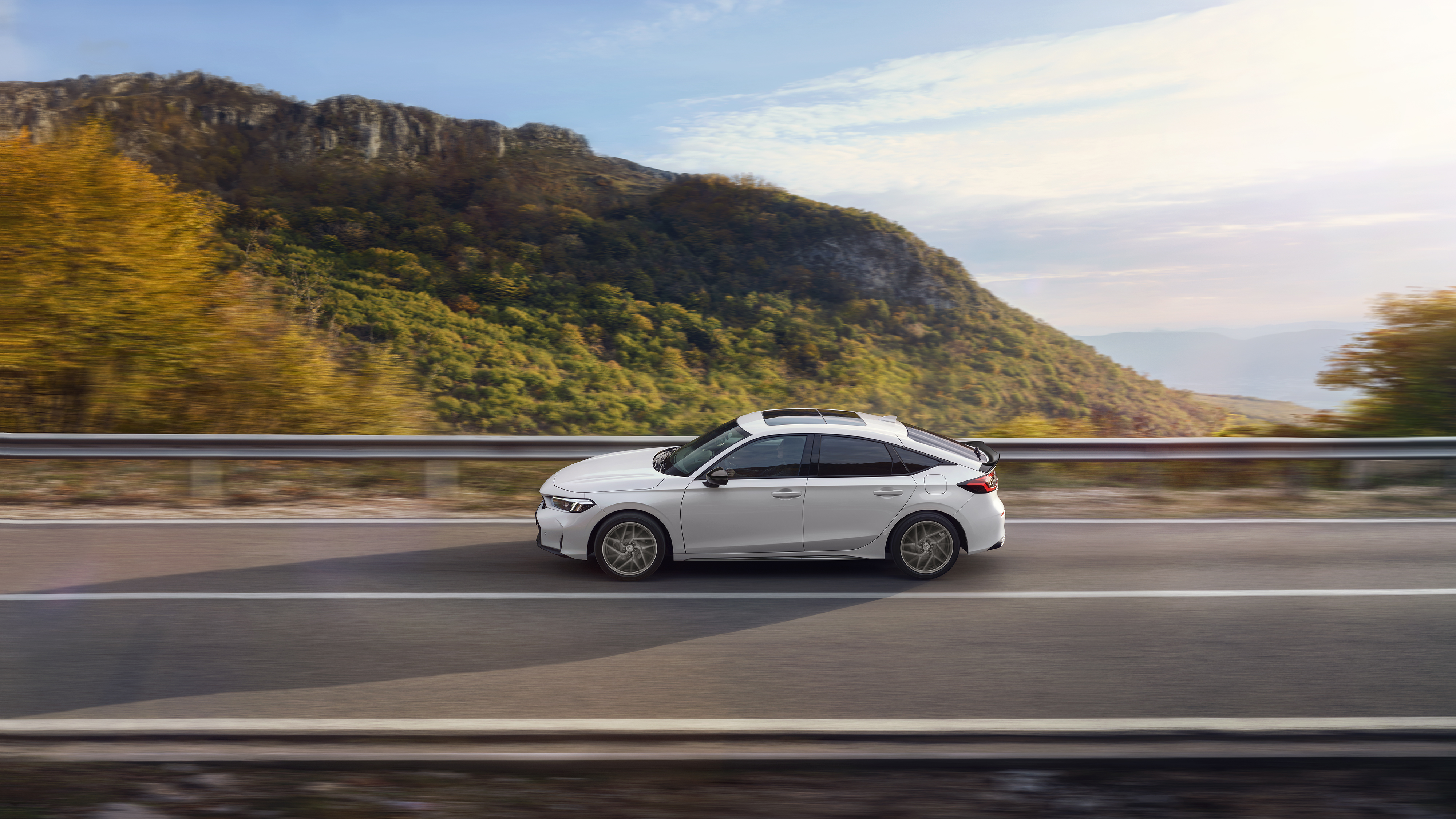 Honda Civic hybride en mouvement sur une autoroute, avec vue panoramique.