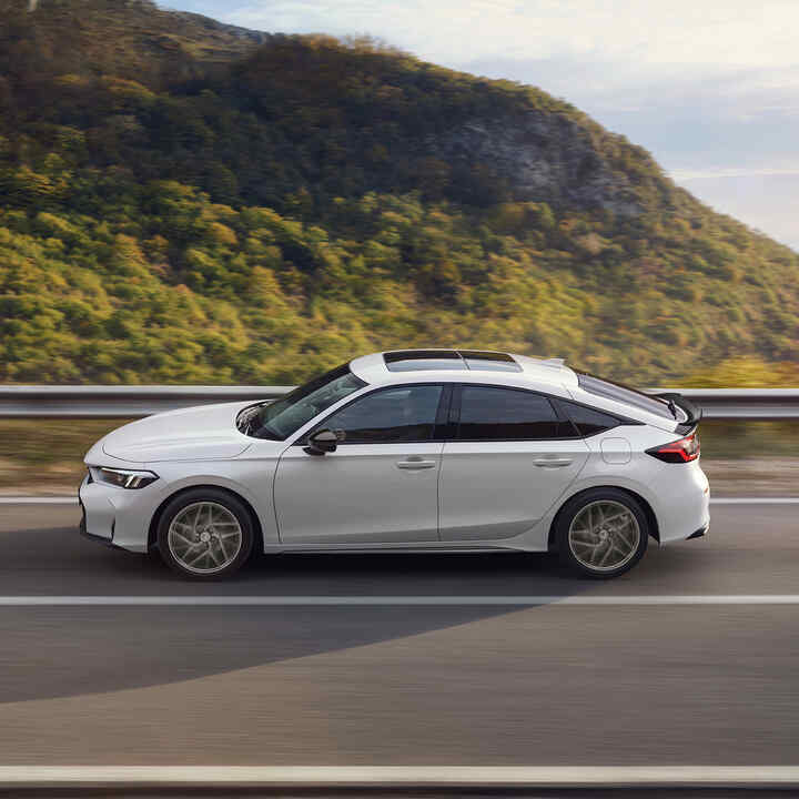 Honda Civic hybride en mouvement sur une autoroute, avec vue panoramique.