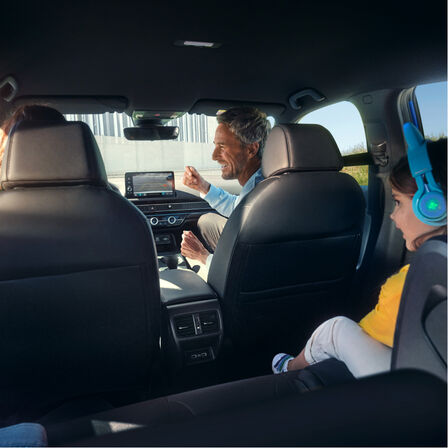Vue d'une famille assise à l'intérieur du véhicule depuis les sièges passagers arrière. 