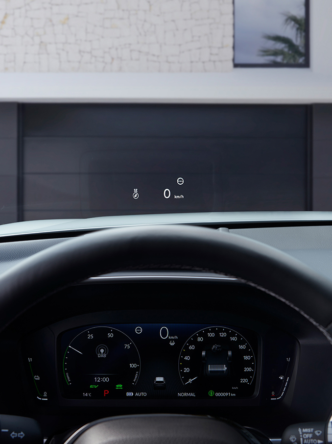 Une vue subjective depuis le siège conducteur montrant un affichage tête haute (HUD) projetant « 50 km/h » et une boussole sur le pare-brise au-dessus d'une route de gravier.
