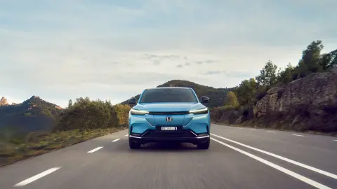 Honda e:Ny1 de face roulant sur la route dans un endroit montagneux. 