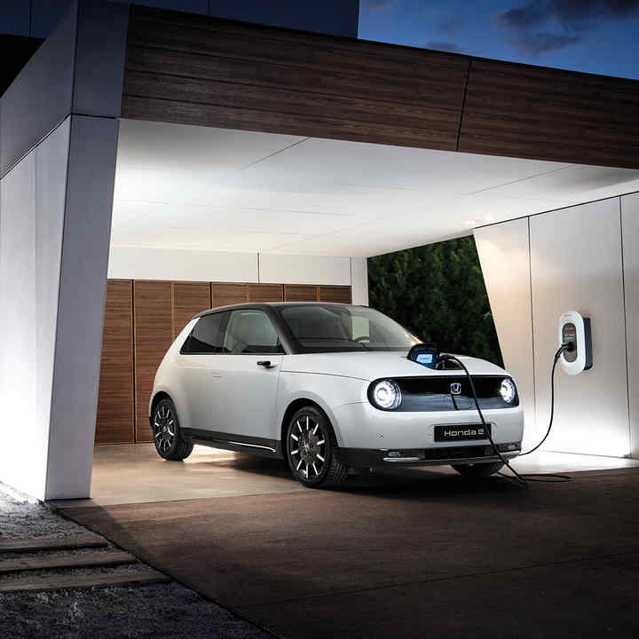 Vue latérale de la Honda e en charge dans un garage.