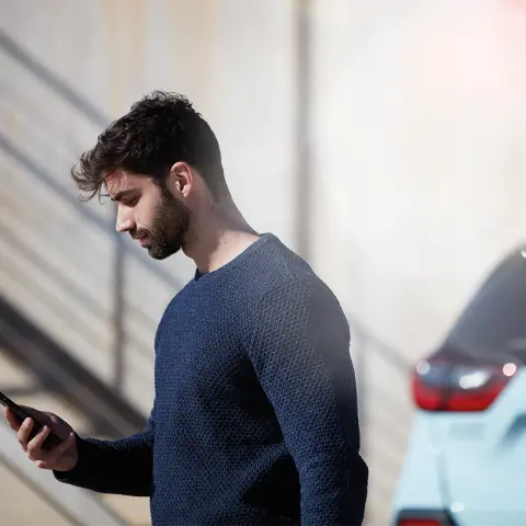 Homme debout à côté de Jazz Crosstar utilisant l'application My Honda Plus.