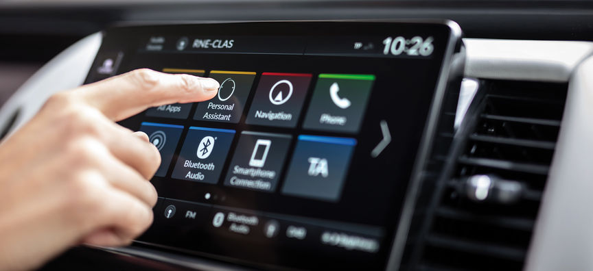 Homme regardant l'application My Honda Plus avec la Honda Jazz Hybrid Crosstar derrière. 