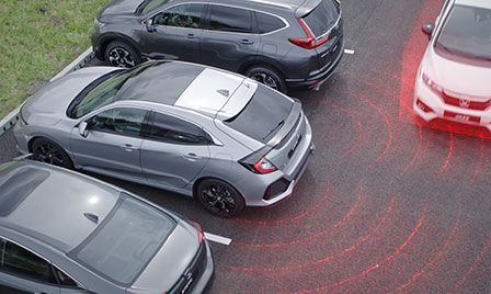 Véhicule à technologie Honda Sensing dans un parking, avec mise en valeur du dispositif d'alerte de véhicule en approche et du système de surveillance de l'angle mort.