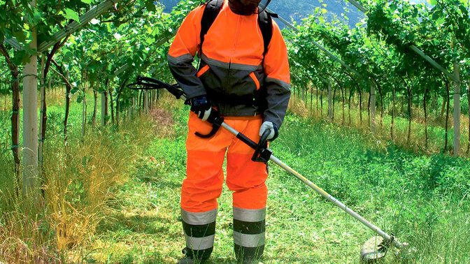 Débroussailleuse à dos en cours d'utilisation dans un champ.