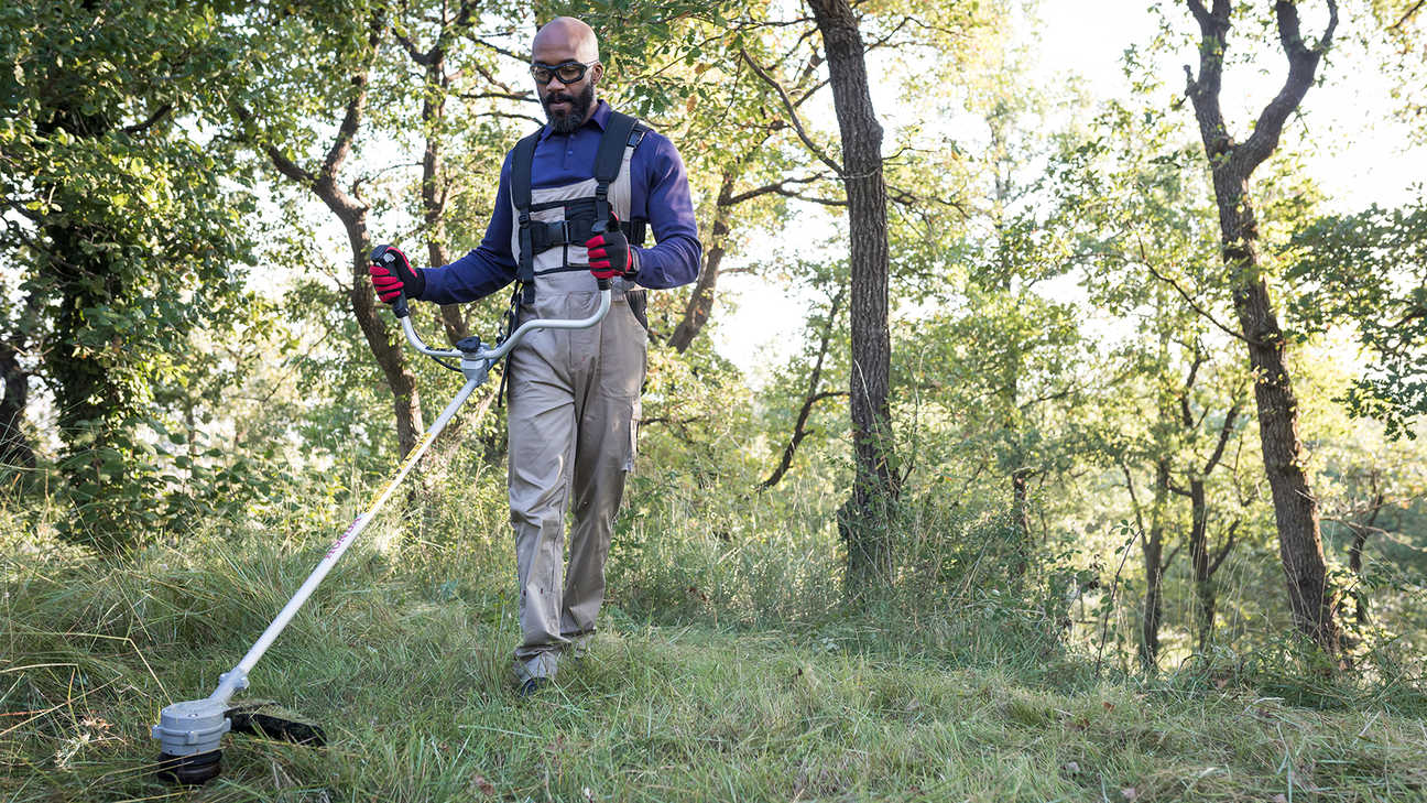 Close up of model trimming a field with Honda cordless brushcutter.