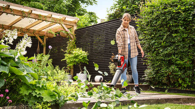 Utilisateur avec un souffleur à batterie dans un jardin