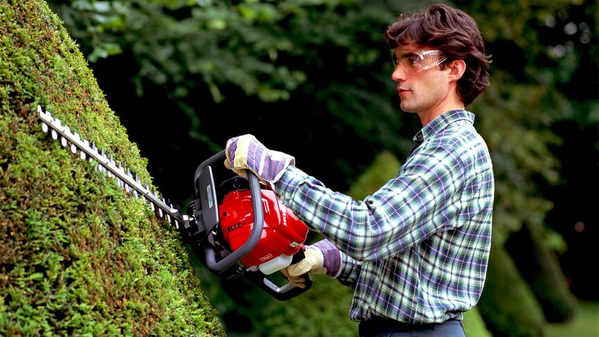 Homme utilisant un taille-haie avec un casque antibruit