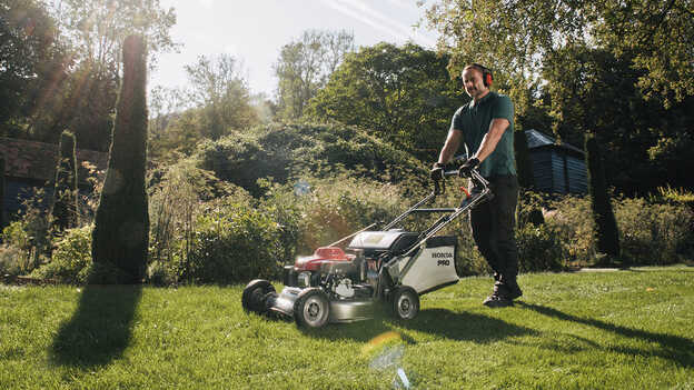 Homme poussant une Honda HRH dans un jardin