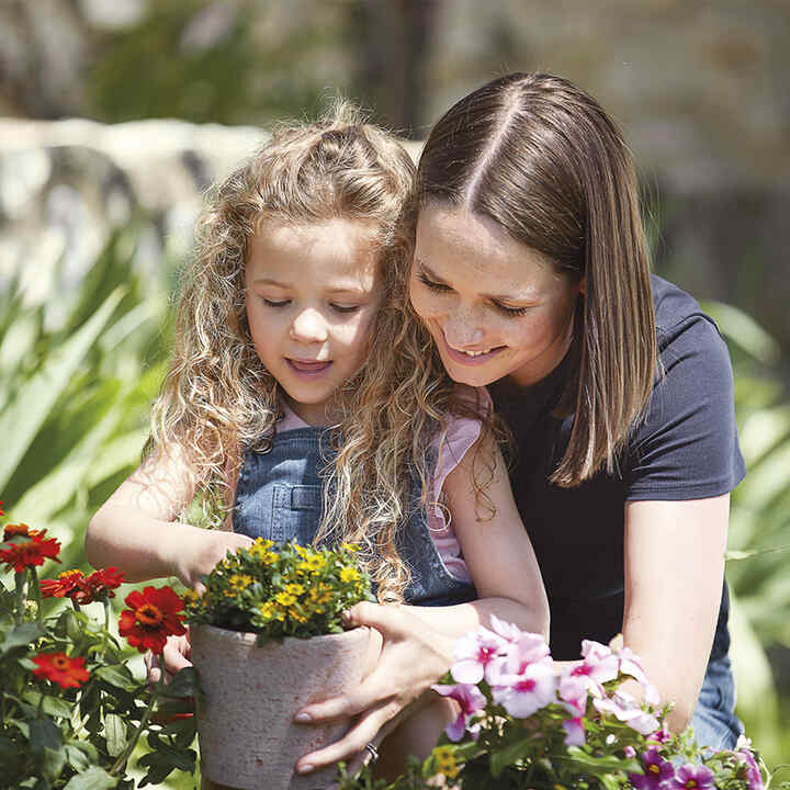 Une mère et sa fille en train de planter des fleurs.