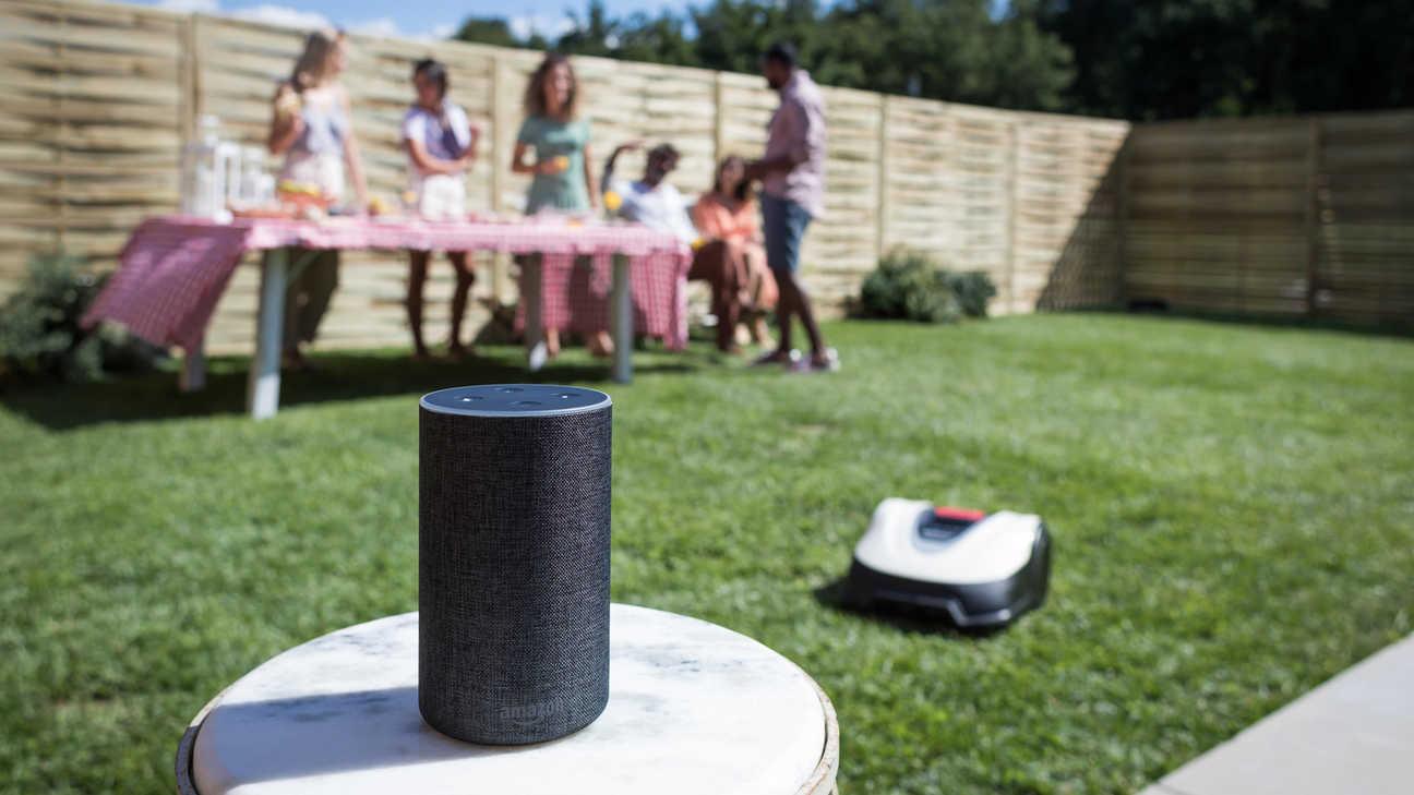 Vue de trois quarts de la Honda Miimo dans un jardin avec des enfants jouant au football en arrière-plan.