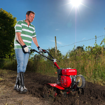Motobineuse compacte, utilisée par un démonstrateur, dans un jardin.