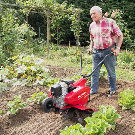 Motoculteur compact, utilisée par un démonstrateur, dans un jardin.