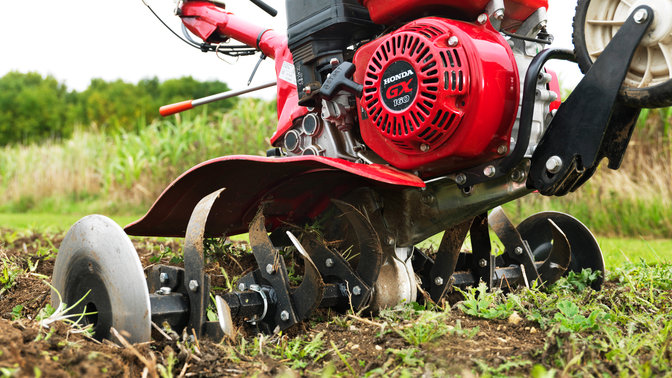 Gros plan d'une motobineuse compacte, mettant en évidence le moteur, dans un jardin.