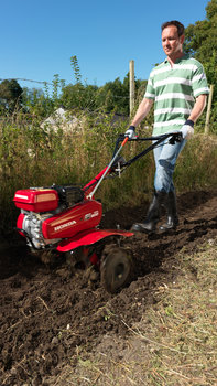 Motobineuse compacte, utilisée par un démonstrateur, dans un jardin.