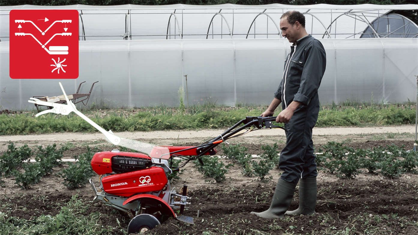 Motoculteur transformable mettant en évidence la poignée réversible, utilisée par un démonstrateur dans un jardin.