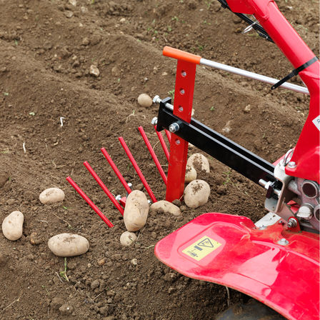 Motoculteur transformable utilisé par un démonstrateur dans un jardin.