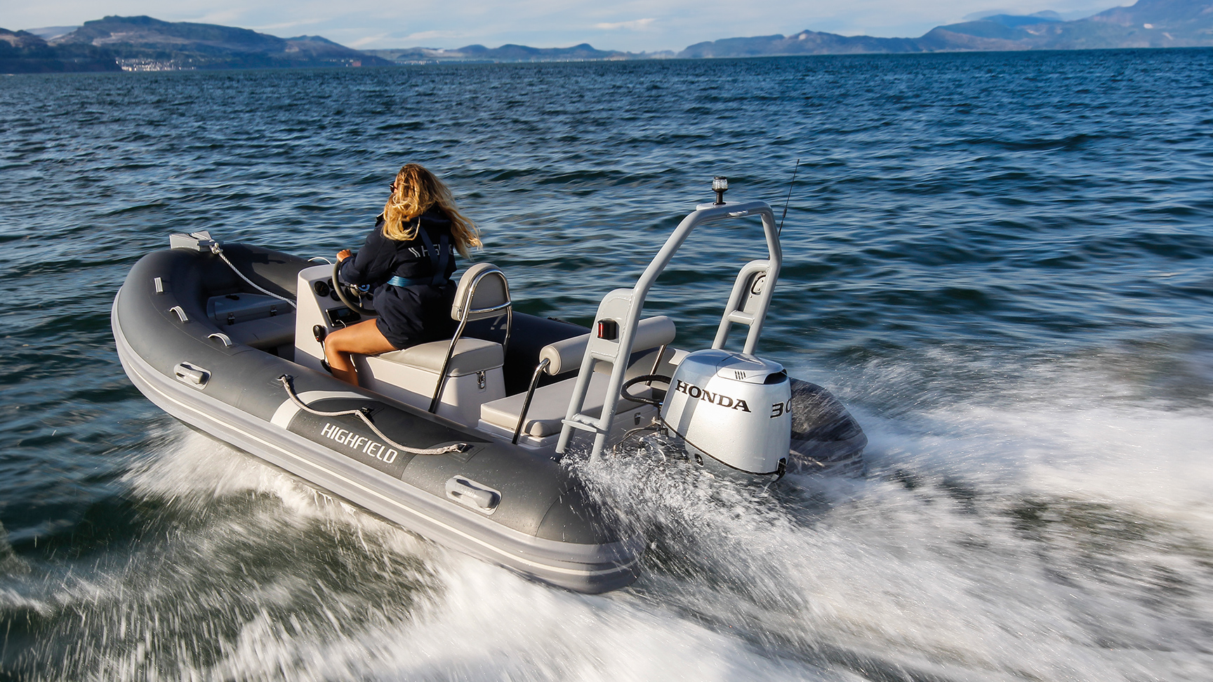 Femme à bord d'un bateau Highfield équipé d'un moteur Honda BF30, en pleine mer.