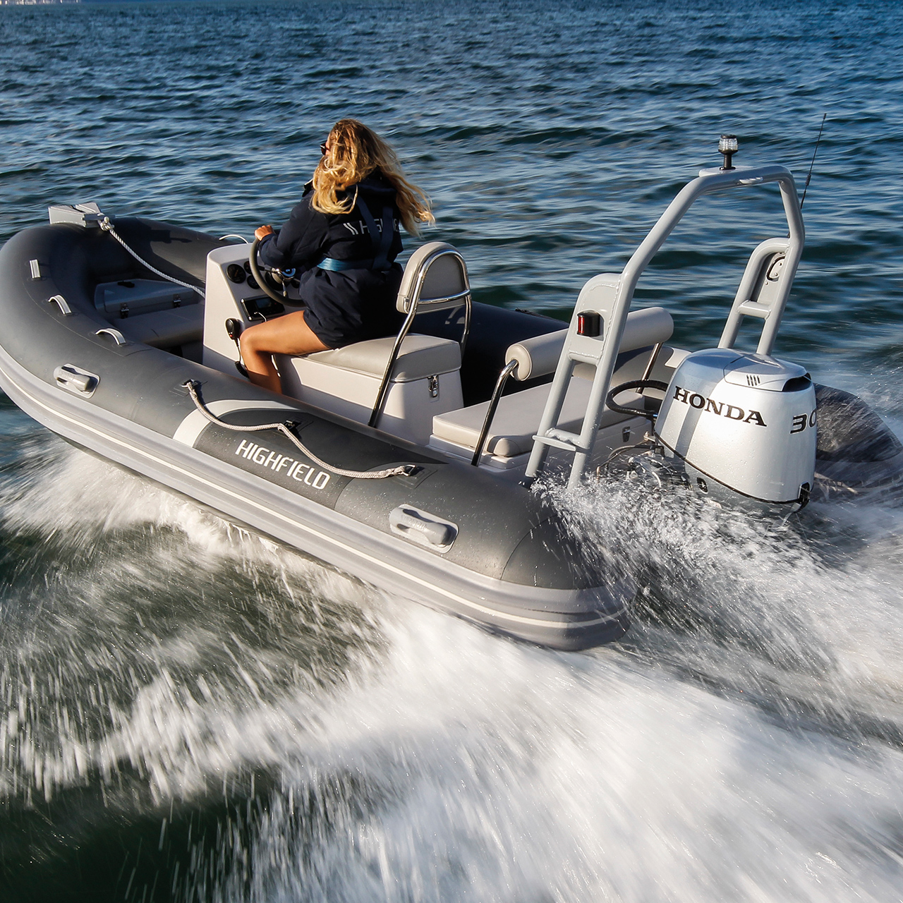 Femme à bord d'un bateau Highfield équipé d'un moteur Honda BF30, en pleine mer.