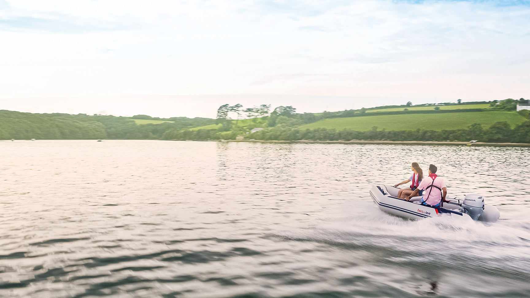 Couple sur un bateau Honwave au bord d'un lac utilisant un moteur Honda BF. 