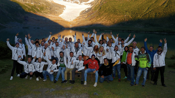 Participants au Honda Adventure Roads dans un moment de célébration au bord de l'eau au coucher du soleil.