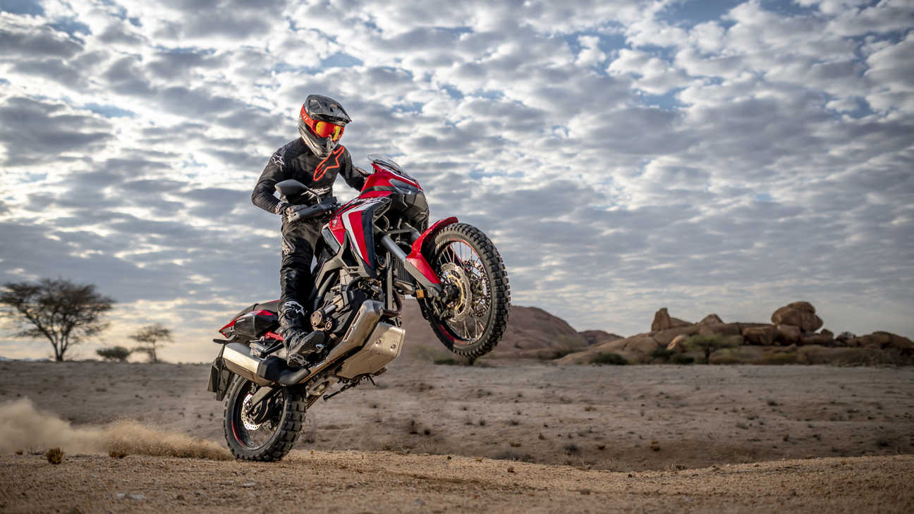 Trail Honda Africa Twin, vue de trois quarts avant droit, sur sa roue arrière dans un paysage désertique