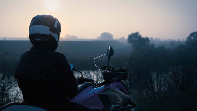 Le pilote assis sur sa Honda NC750X, garée en zone rurale.
