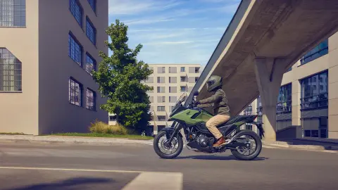 Plan latéral d'un mannequin conduisant la moto NC750X en milieu urbain.