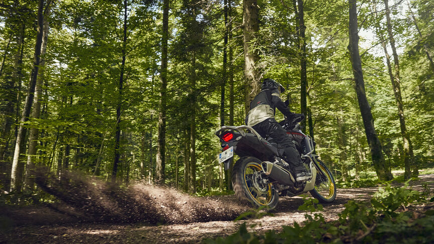Mannequin conduisant la moto XL750 Transalp en forêt.