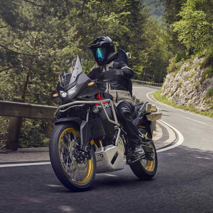 Modèle conduisant la moto XL750 Transalp dans un endroit montagneux.