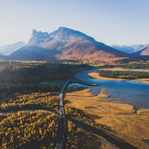 Vue prise par drone sur un paysage scandinave norvégien traditionnel montagneux en été avec route, massifs et fjords sous un ciel bleu, nord de la Norvège, comté de Finnmark