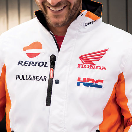 Homme souriant portant un blouson de course Honda.