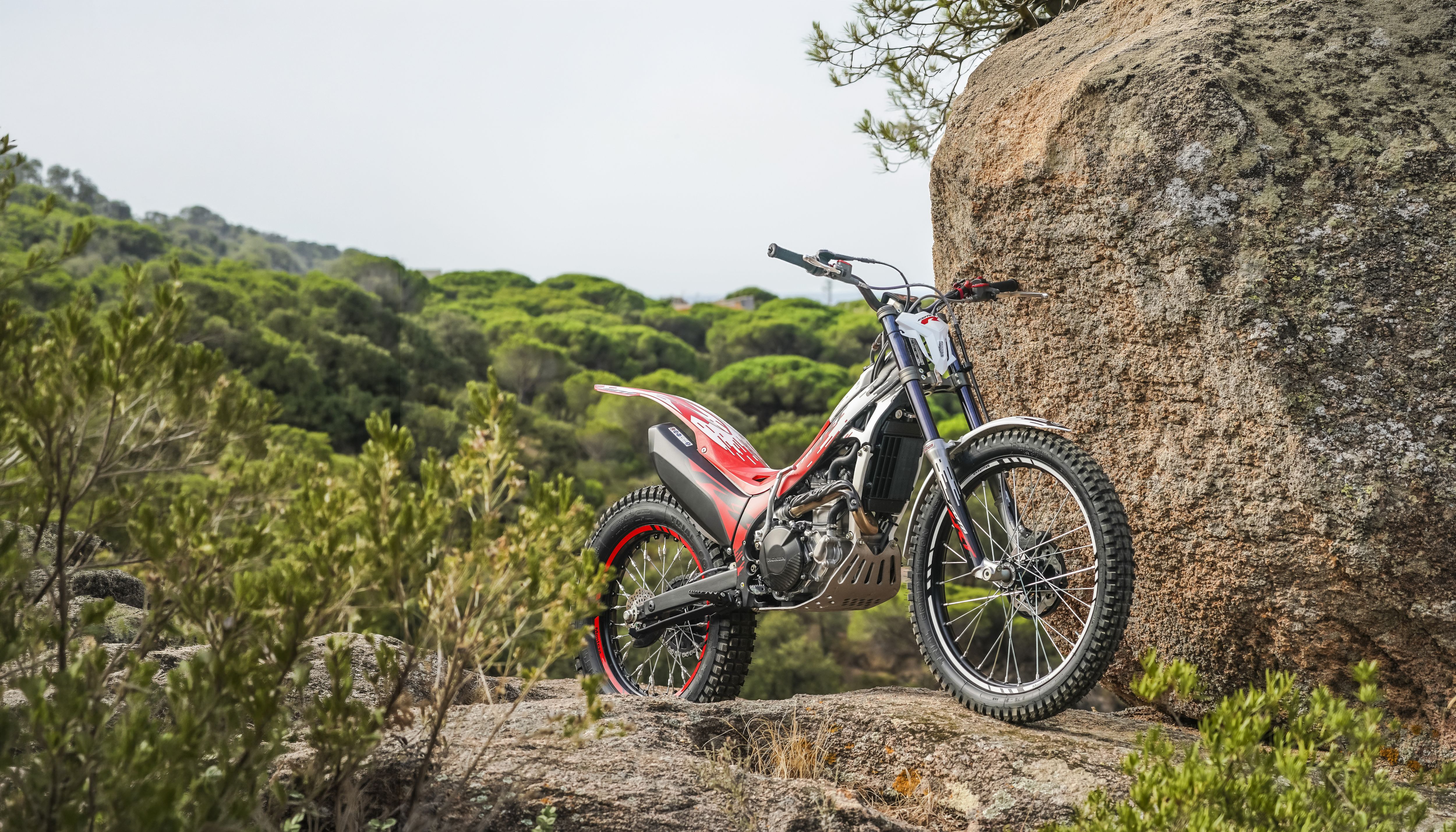 Moto de trial Montesa Cota 301RR à l’arrêt sur un terrain rocailleux en extérieur.