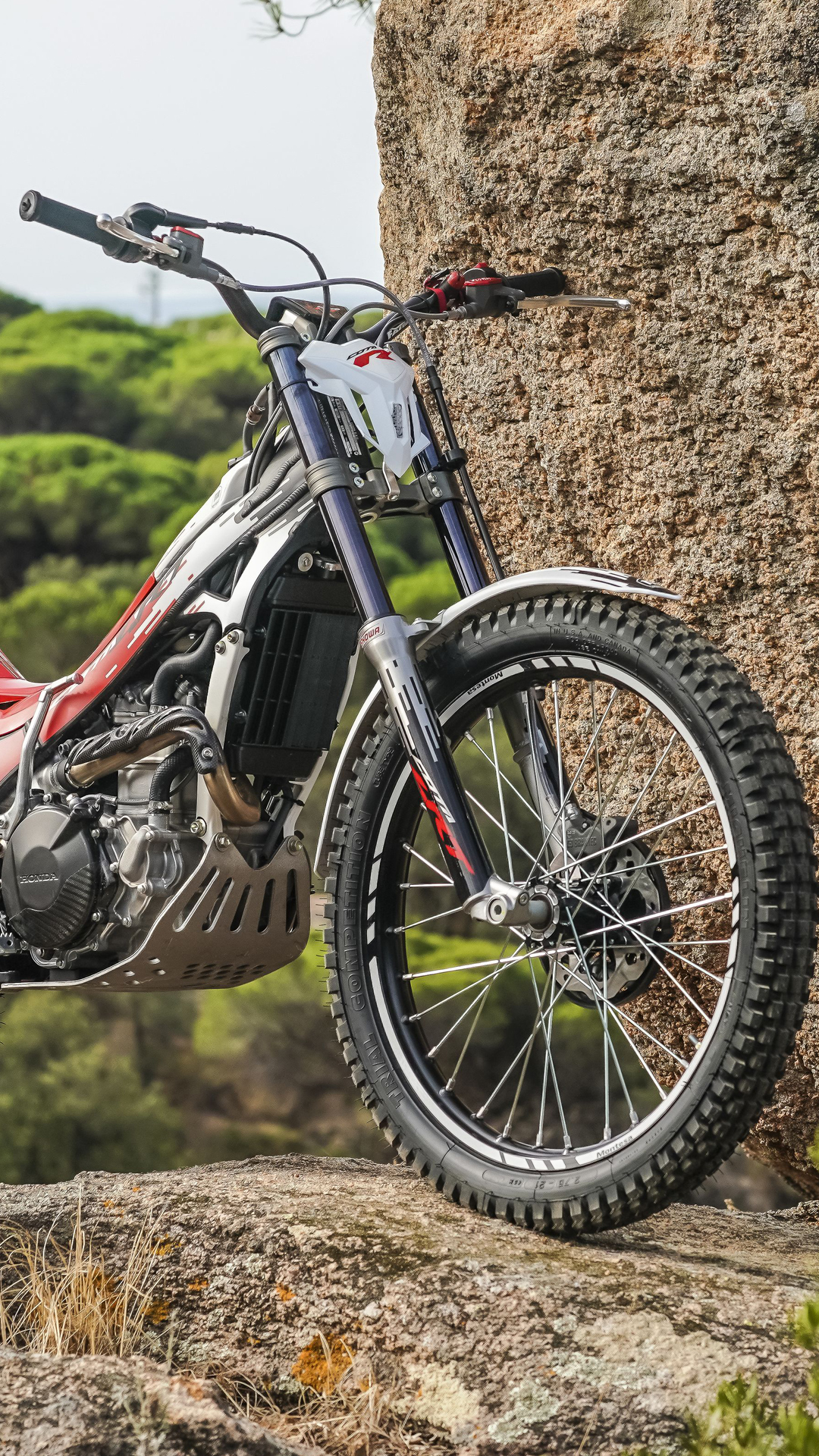 Moto de trial Montesa Cota 301RR à l’arrêt sur un terrain rocailleux en extérieur.