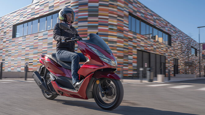 Prise de vue dynamique de trois quarts avant du PCX125 avec motard