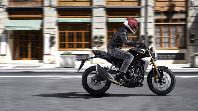 Plan latéral d'une Honda CB300R Neo Sports Café en mouvement sur route.