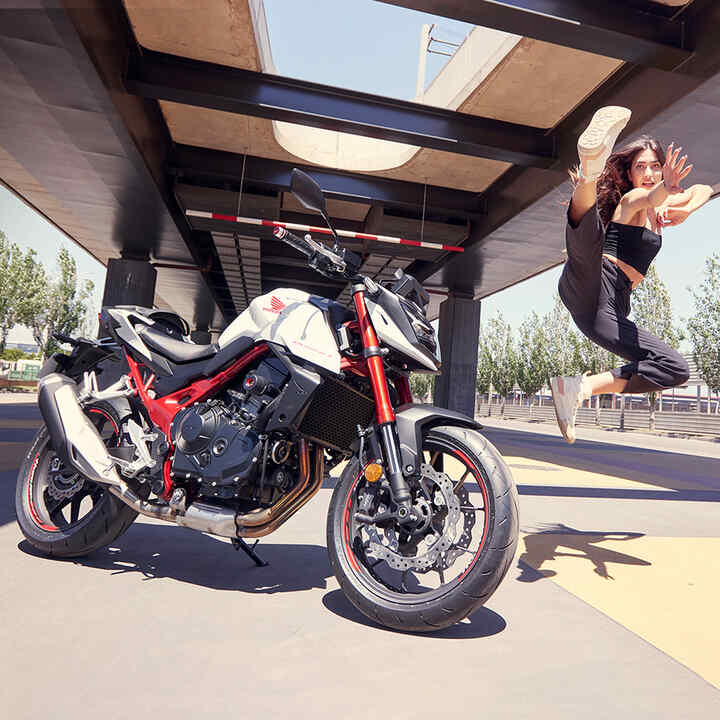 Danseuse sautant en l'air à côté de la moto roadster streefighter Honda CB750 Hornet - permis A2