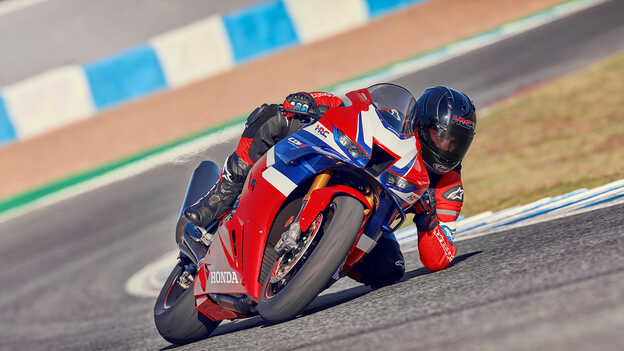 Prise de vue dynamique de la Honda CBR1000RR-R Fireblade sur piste avec motard accélérant en sortie de virage.