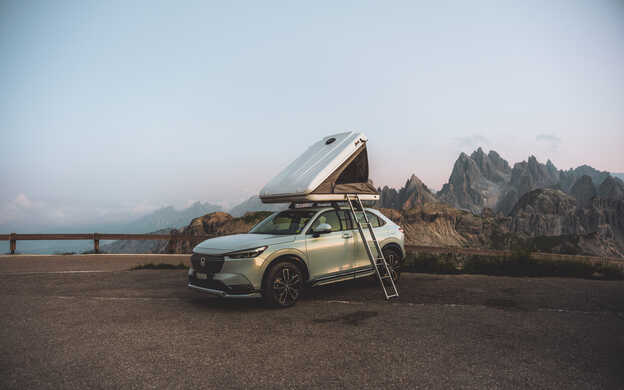 HR-V e:HEV Hybrid avec une tente de toit et les Dolomites en arrière-plan