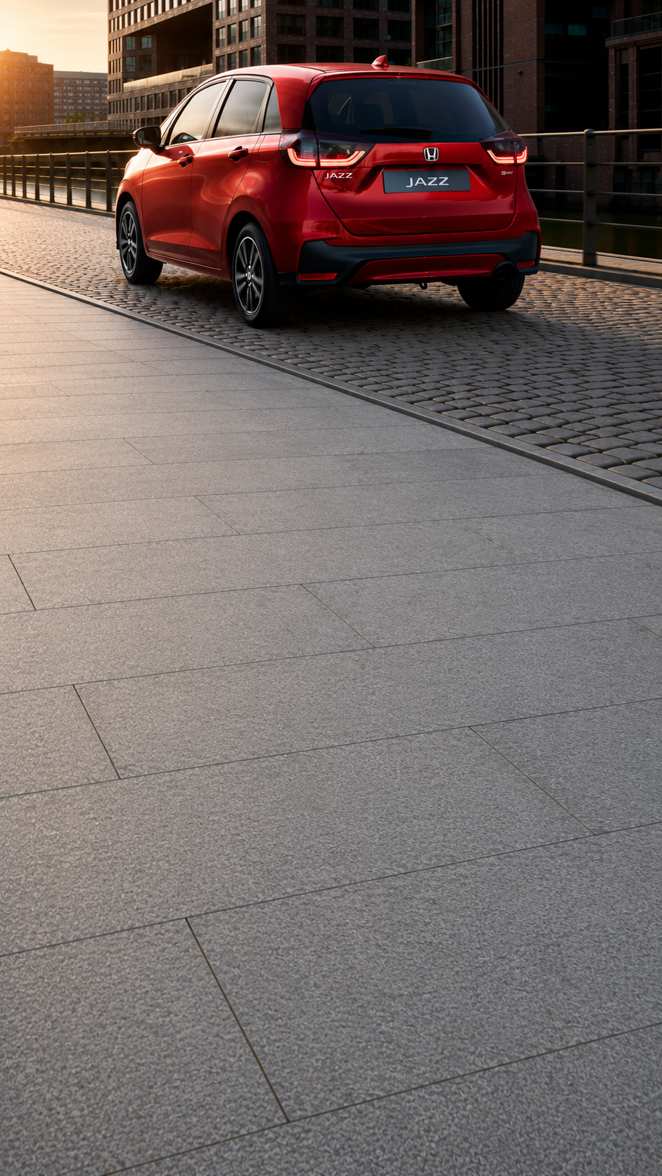 Honda Jazz en Premium Crystal Red Metallic roulant sur une route urbaine, vue de l'arrière